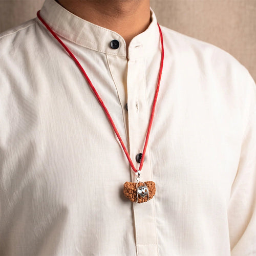 VASTUKOSHA 1 Mukhi Rudraksha bead in a unique Kaju shape, worn as a pendant on a red thread over a white shirt.