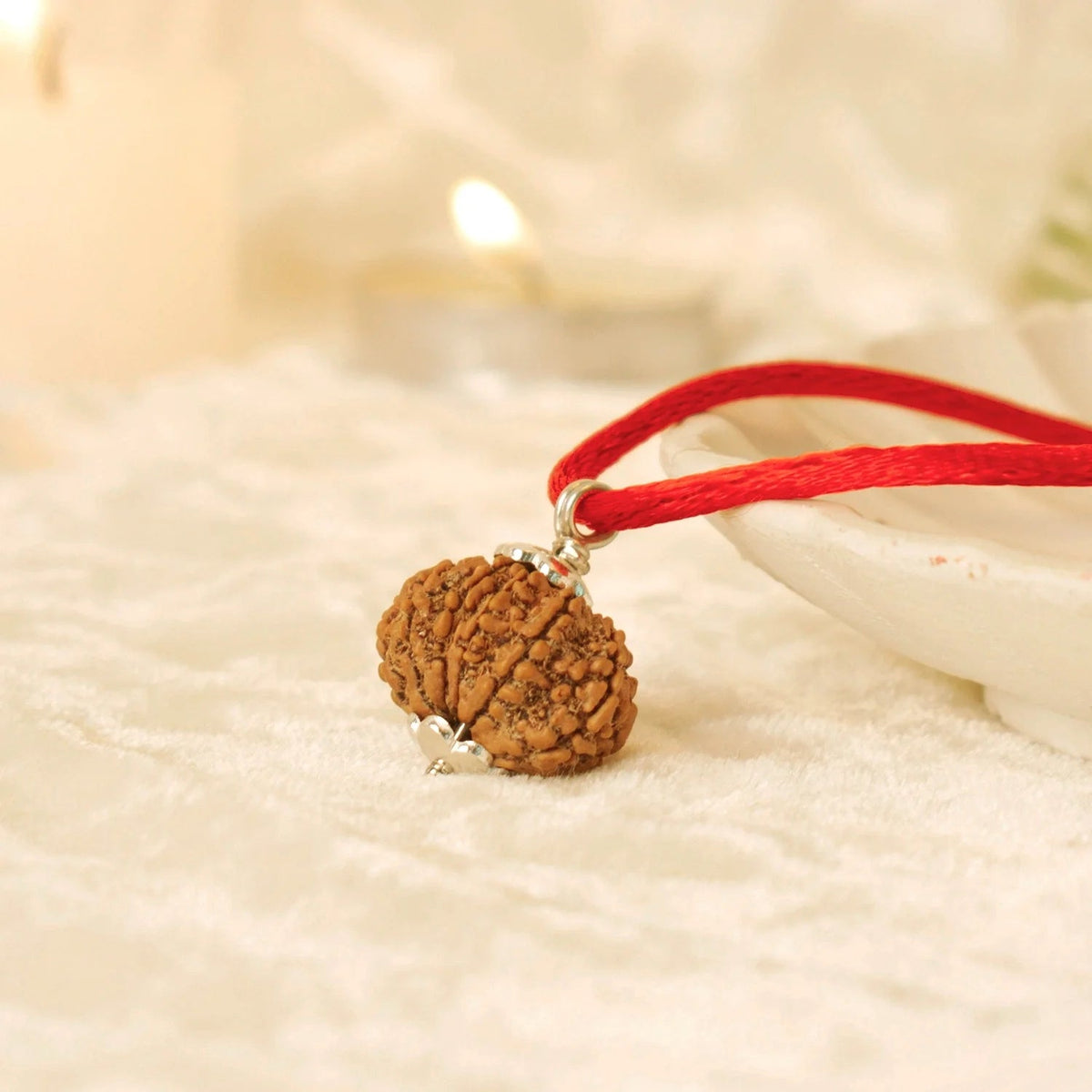 VASTUKOSHA 13 Mukhi Nepal Rudraksha bead on a red cord, featuring natural texture and silver-tone metal cap.