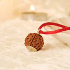 VASTUKOSHA 4 Mukhi Nepal Rudraksha bead pendant on a red thread, featuring natural texture and silver cap detail.