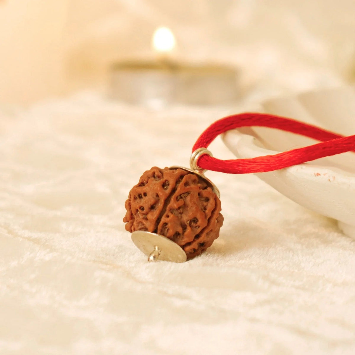 VASTUKOSHA 4 Mukhi Nepal Rudraksha bead pendant on a red thread, featuring natural texture and silver cap detail.