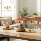 VASTUKOSHA 7 chakra conical pyramid with layered crystals on a wooden table with a hand hovering above for energy