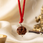 VASTUKOSHA 7 Mukhi Nepal origin Rudraksha bead pendant with silver cap on a red thread against a soft cream background