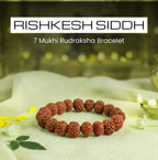 VASTUKOSHA 7 Mukhi Rudraksha bead bracelet for wealth and luck, resting on a white cloth with a lit diya lamp
