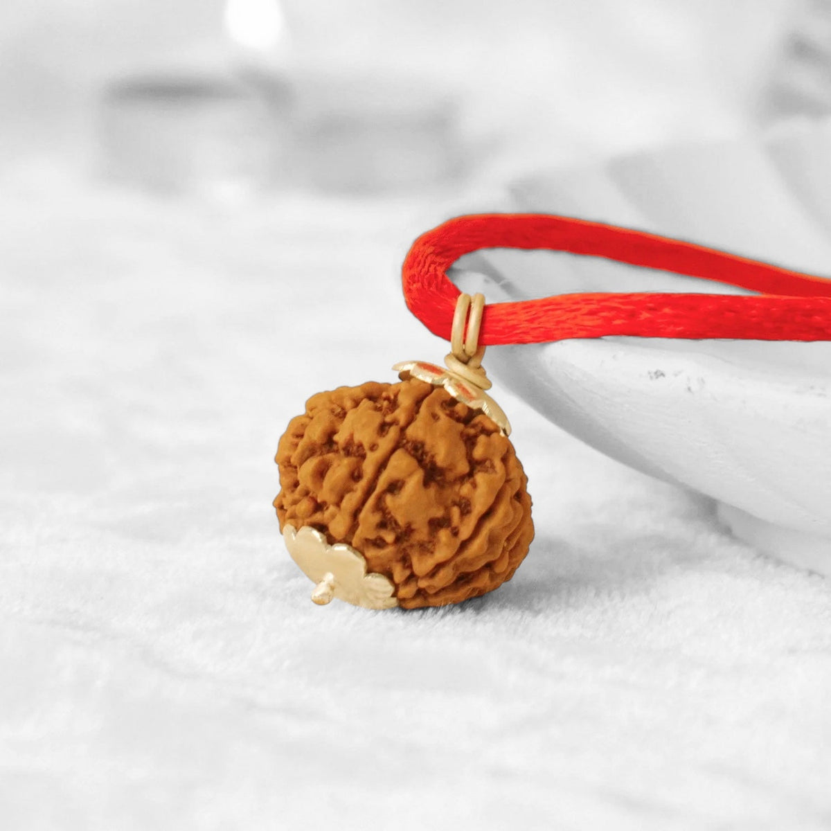 VASTUKOSHA 7 Mukhi Nepal Rudraksha bead pendant with gold caps on a red thread for spiritual practice and prosperity.
