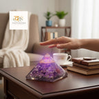 VASTUKOSHA amethyst orgonite pyramid with copper accents on a wooden table, hand hovering for energy healing.