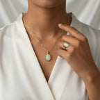 VASTUKOSHA Australian fire opal pendant and matching ring set in gold, worn by a woman in a white blouse.