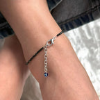 VASTUKOSHA black tourmaline beaded anklet with a blue evil eye charm worn on a person's ankle