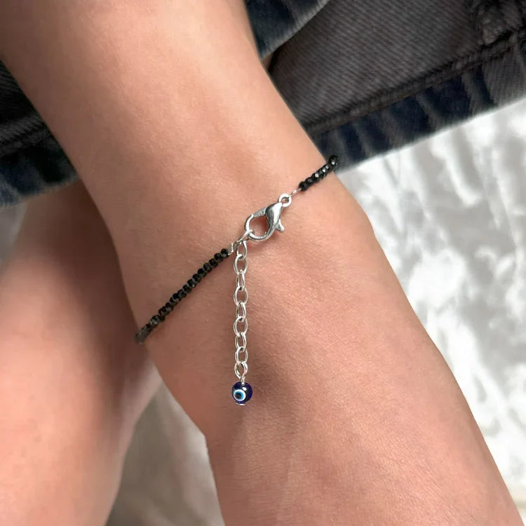 VASTUKOSHA black tourmaline beaded anklet with a blue evil eye charm worn on a person's ankle