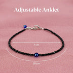 VASTUKOSHA black tourmaline beaded anklet with a blue evil eye charm and adjustable silver-tone clasp on pink fabric.