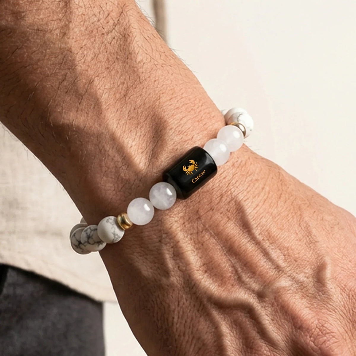 VASTUKOSHA Cancer zodiac bracelet featuring white Howlite and Milky Quartz beads with a black Cancer sign charm on a wrist