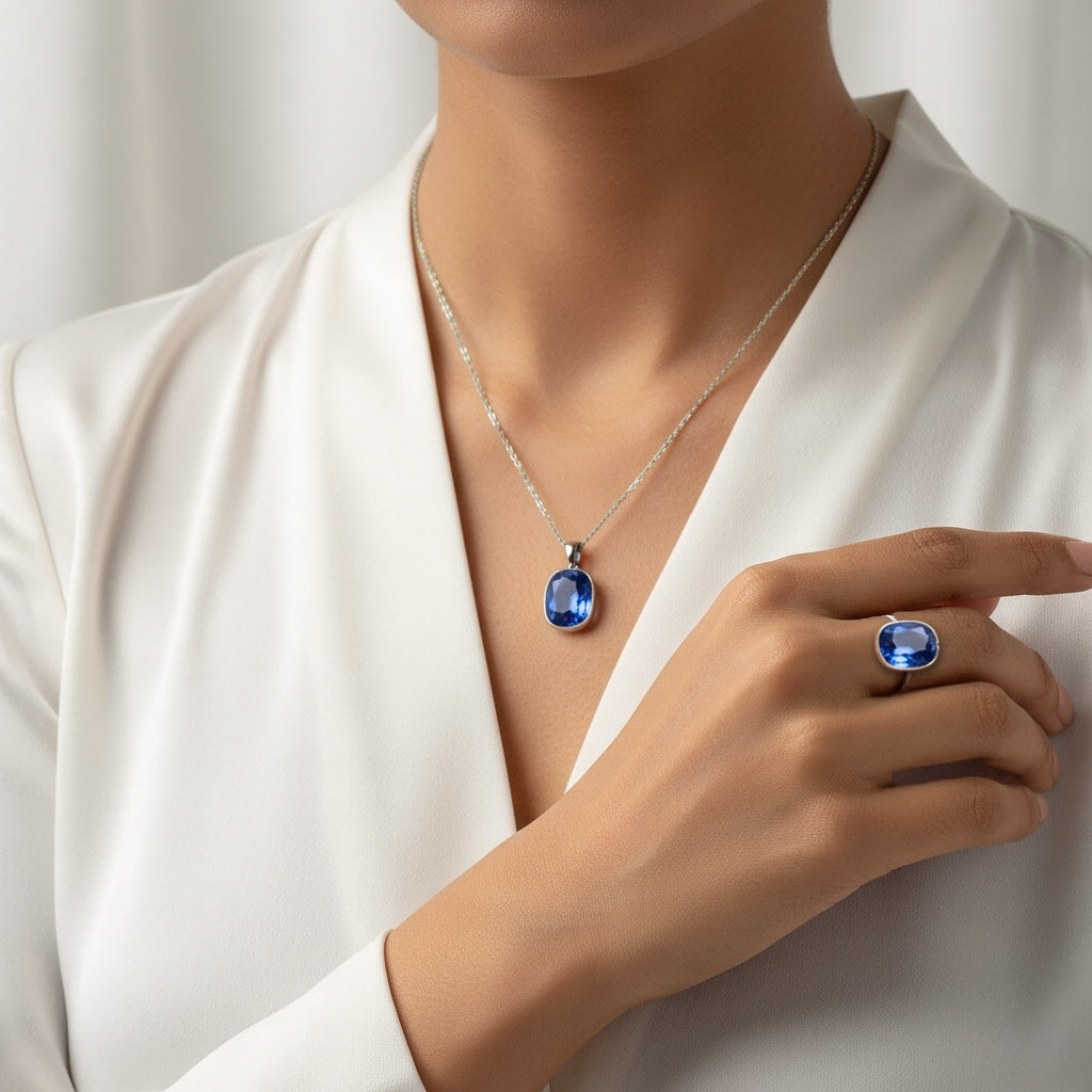A person wearing a VASTUKOSHA natural Ceylon Neelam blue sapphire pendant and matching ring in a silver setting.