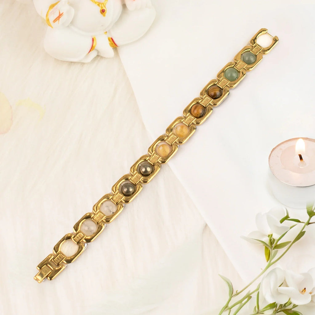 VASTUKOSHA Dhan Yog bracelet featuring genuine crystals in gold-plated metal links on a white surface with a candle.