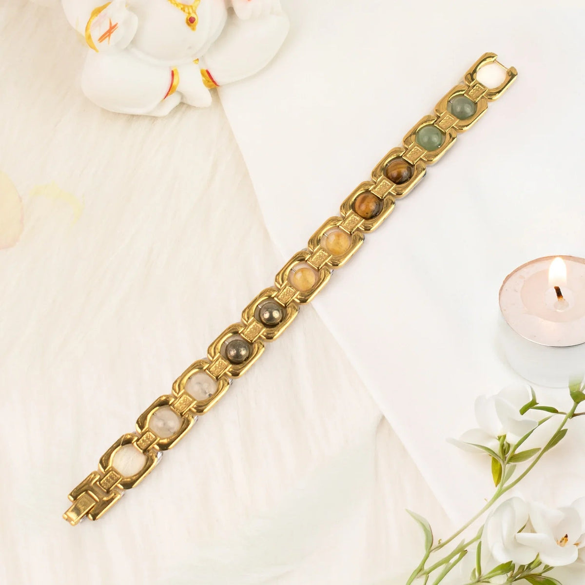 VASTUKOSHA Dhan Yog bracelet featuring genuine crystals in gold-plated metal links on a white surface with a candle.