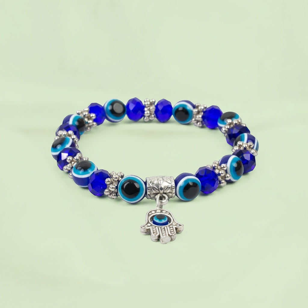 VASTUKOSHA Evil Eye Hamsa bracelet with blue glass beads and a silver-toned Hamsa hand charm on a light green background