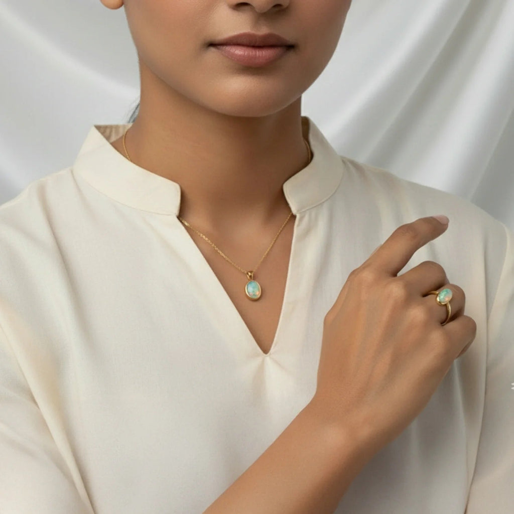 VASTUKOSHA fire opal pendant necklace and matching ring set worn by a woman in a cream blouse against a draped backdrop