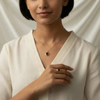 Woman wearing a VASTUKOSHA gold necklace and ring set with deep red natural garnet gemstones against a white backdrop.