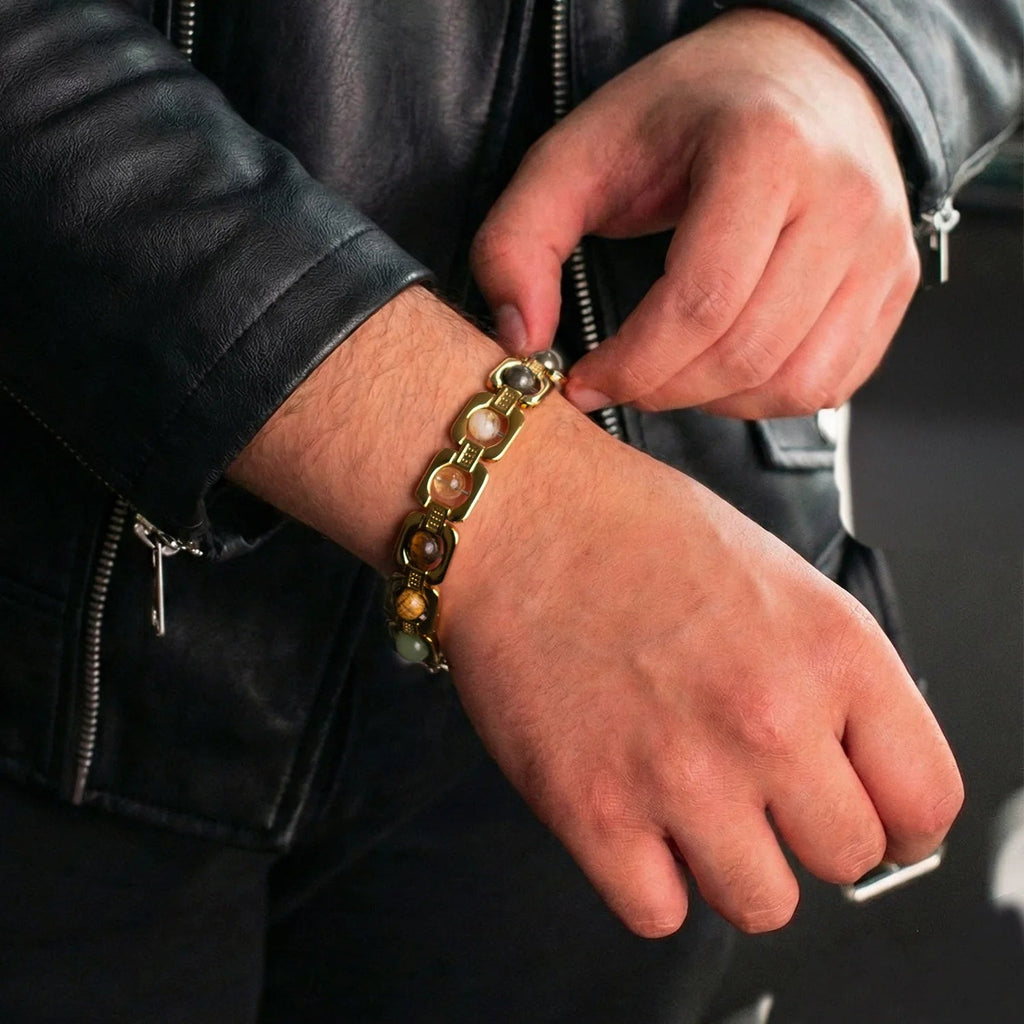 VASTUKOSHA gold-plated Dhan Yog bracelet with genuine crystals worn on a man's wrist with a black leather jacket.
