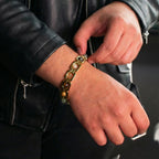 VASTUKOSHA gold-plated Dhan Yog bracelet with genuine crystals worn on a man's wrist with a black leather jacket.