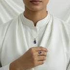 VASTUKOSHA Iolite gemstone pendant and matching ring set in silver, worn by a person in a white blouse.