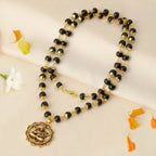 VASTUKOSHA Karungali mala with black ebony beads, gold-plated caps, and a Hanuman Kavach pendant on a silk cloth.