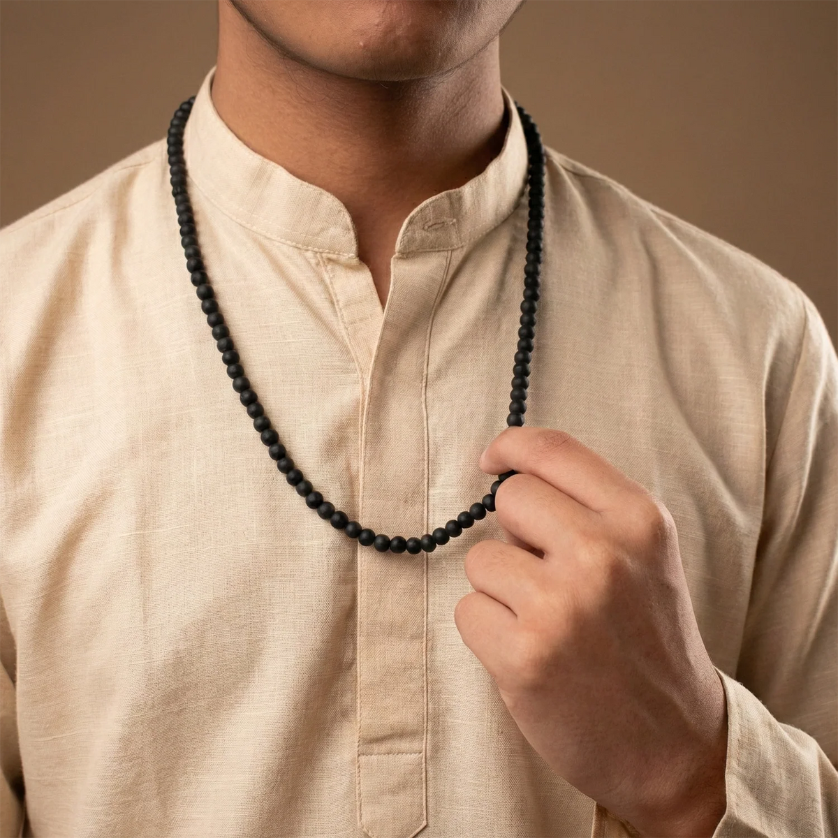 VASTUKOSHA Karungali mala necklace made of 6mm black ebony wood beads worn by a person in a beige kurta