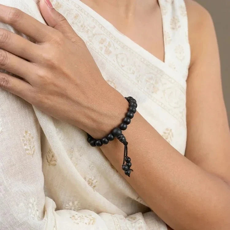 VASTUKOSHA Karungali wood bead bracelet worn on a woman's wrist, featuring dark ebony beads and a traditional knotted cord.