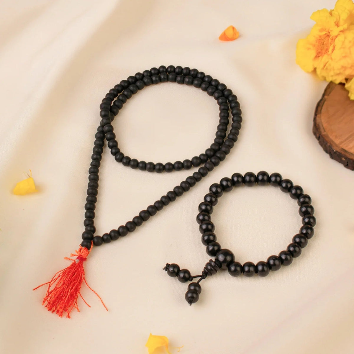 VASTUKOSHA Karungali wood mala and bracelet set with black beads and a red tassel on a cream fabric background.
