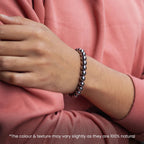 VASTUKOSHA Karz Mukti bracelet made of polished silver hematite beads worn on a wrist with a pink long-sleeve shirt.