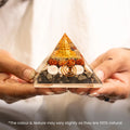 VASTUKOSHA Lakshmi Yantra pyramid with gold-tone symbol, rudraksha beads, and natural stones held in hands