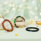 VASTUKOSHA Maha Dhan Yog Combo featuring a 5 Mukhi Rudraksha bracelet, a multi-stone prosperity bracelet, and an Evil Eye black obsidian bracelet on a light green surface.