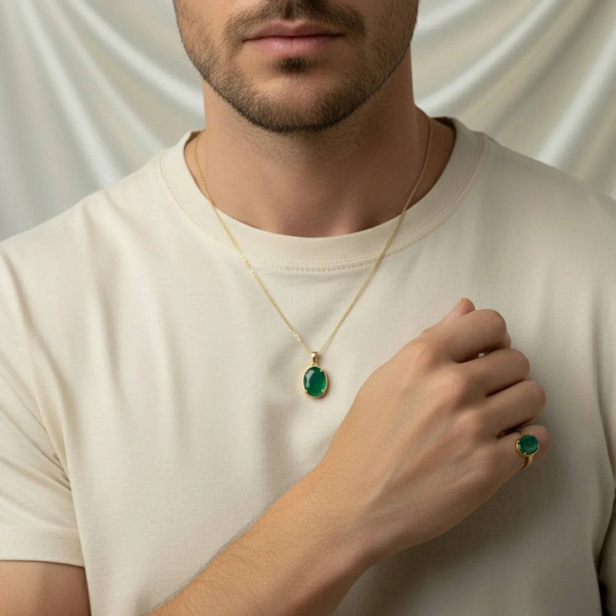 VASTUKOSHA natural emerald pendant and ring set in gold, worn by a man in a cream t-shirt for spiritual practice.