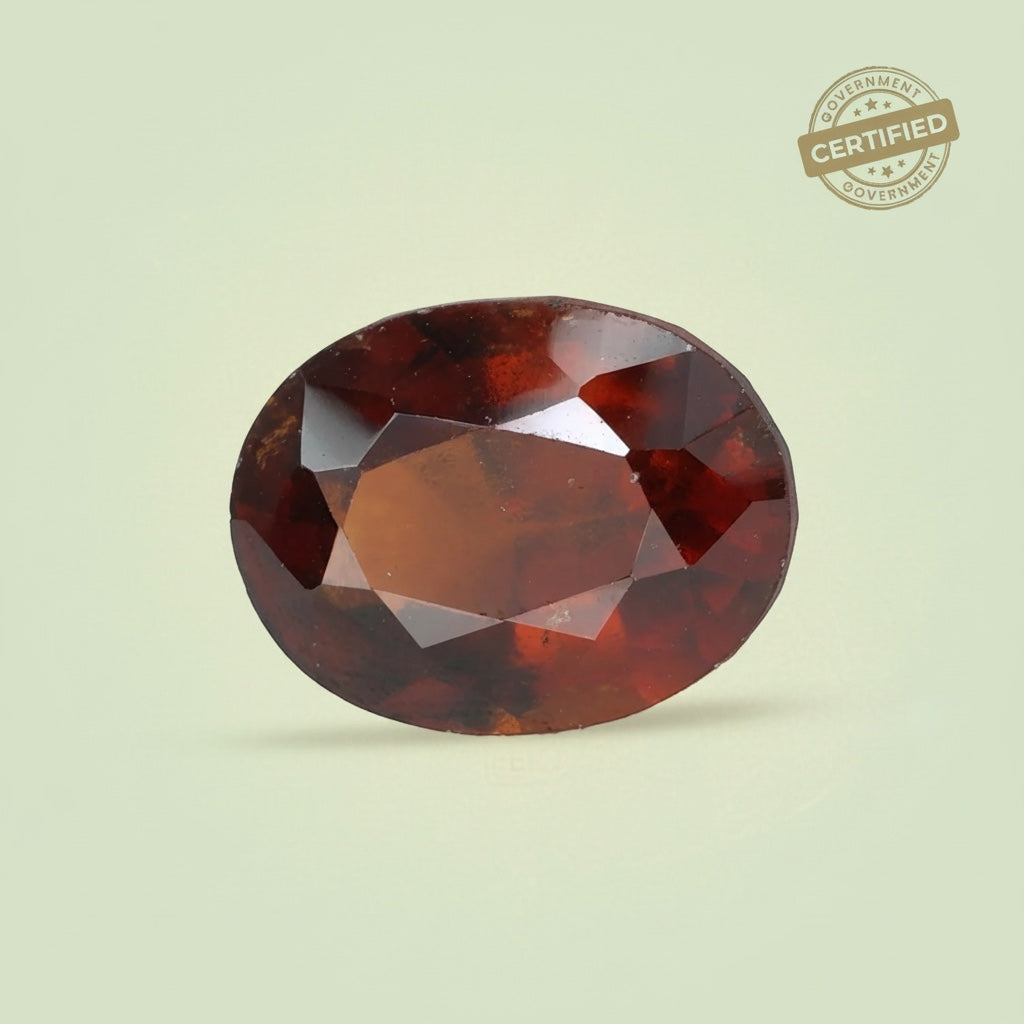 Oval-cut natural Hessonite gemstone by VASTUKOSHA with a deep honey-brown colour and faceted surface.