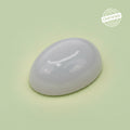 VASTUKOSHA natural oval moonstone gemstone with a smooth polished surface on a light green background