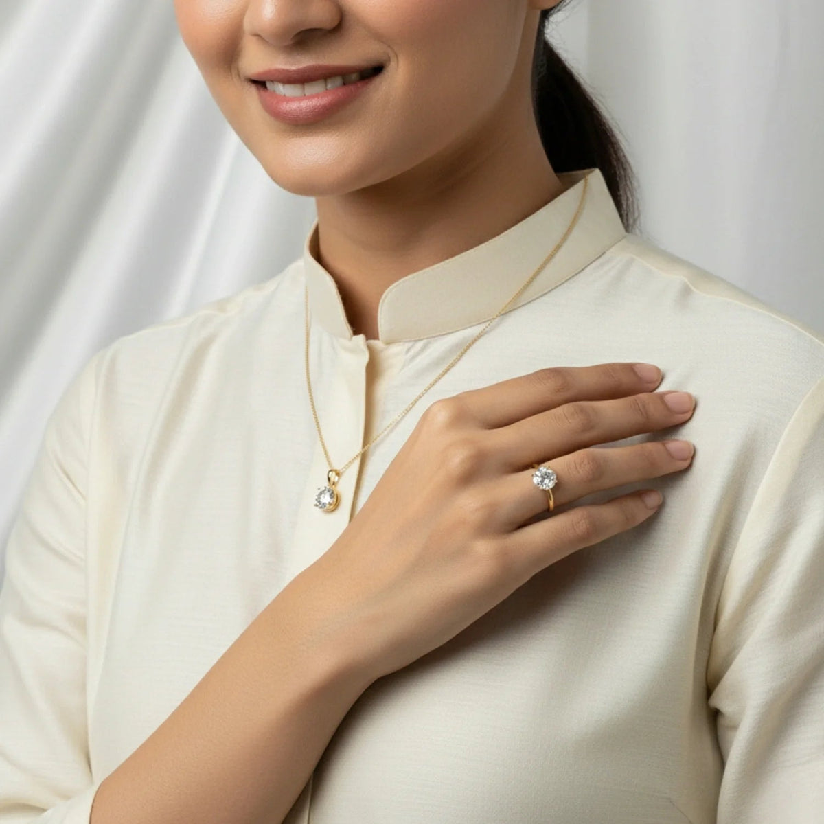 VASTUKOSHA natural zircon gemstone set in a minimalist gold ring and matching pendant worn by a woman in cream attire.