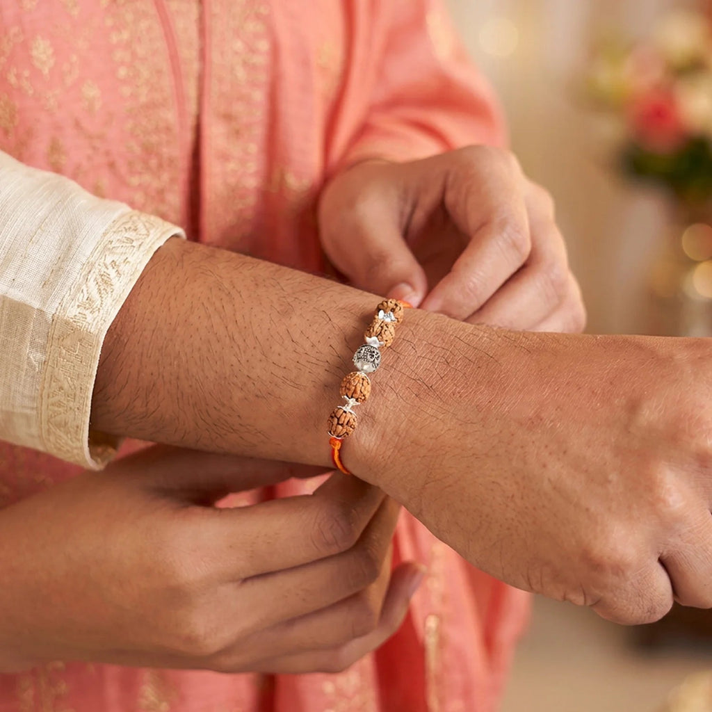 VASTUKOSHA OM Rudraksha Rakhi featuring a 5 Mukhi bead and sacred OM symbol tied on a brother's wrist for celebration.