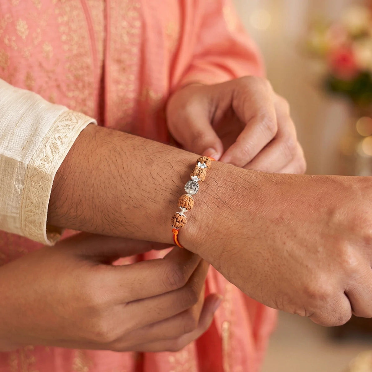 VASTUKOSHA OM Rudraksha Rakhi featuring a 5 Mukhi bead and sacred OM symbol tied on a brother's wrist for celebration.