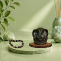 VASTUKOSHA Pyrite Ganesha idol and Wealth OM Pyrite and lava stone bracelet displayed on a green marble platform.