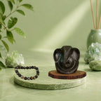 VASTUKOSHA Pyrite Ganesha idol and Wealth OM Pyrite and lava stone bracelet displayed on a green marble platform.