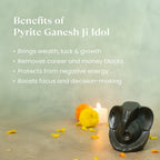 VASTUKOSHA Pyrite Ganesha idol on a surface with marigold flowers and a candle, highlighting spiritual benefits.