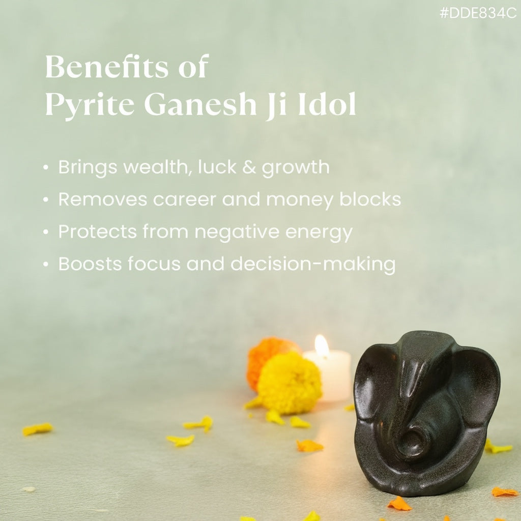 VASTUKOSHA Pyrite Ganesha idol on a surface with marigold flowers and a candle, promoting spiritual benefits.