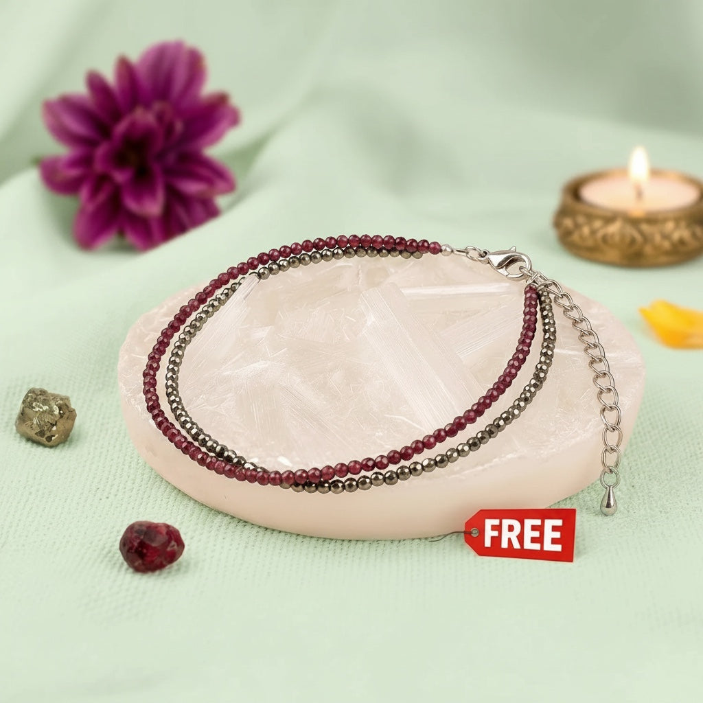 VASTUKOSHA Love and Money anklet featuring Pyrite and Garnet beads resting on a raw Selenite plate with a free tag.