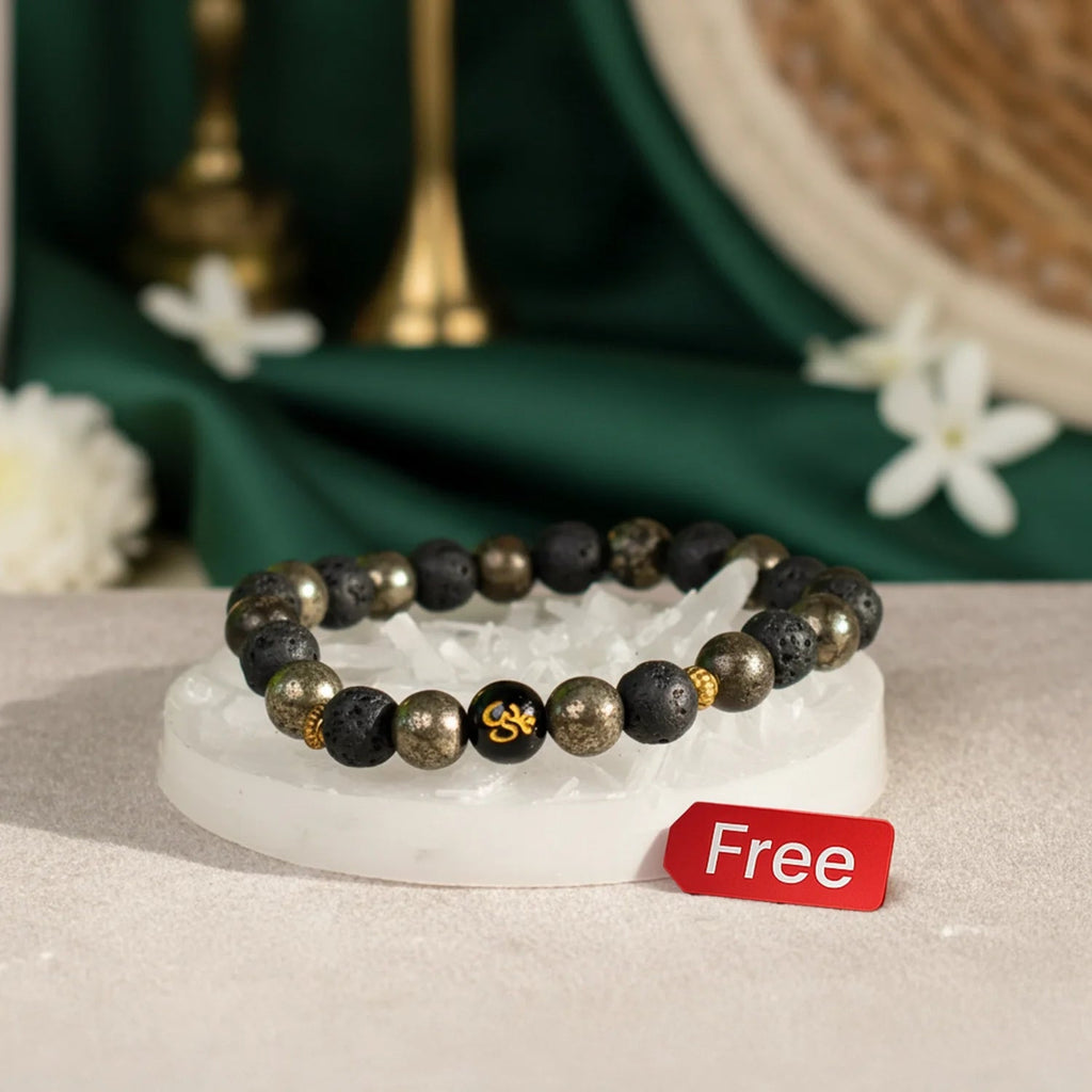 VASTUKOSHA wealth bracelet with pyrite, lava beads, and Om symbol resting on a raw selenite cleansing plate.