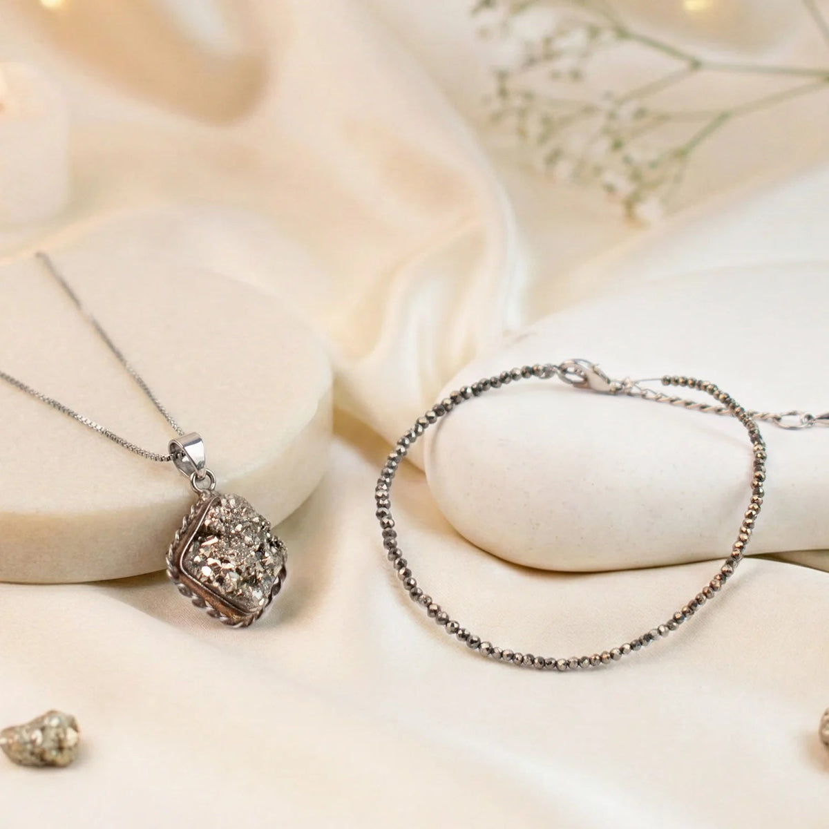 VASTUKOSHA Princess Combo featuring a raw capped pyrite pendant and a delicate pyrite bead anklet on a silk background.