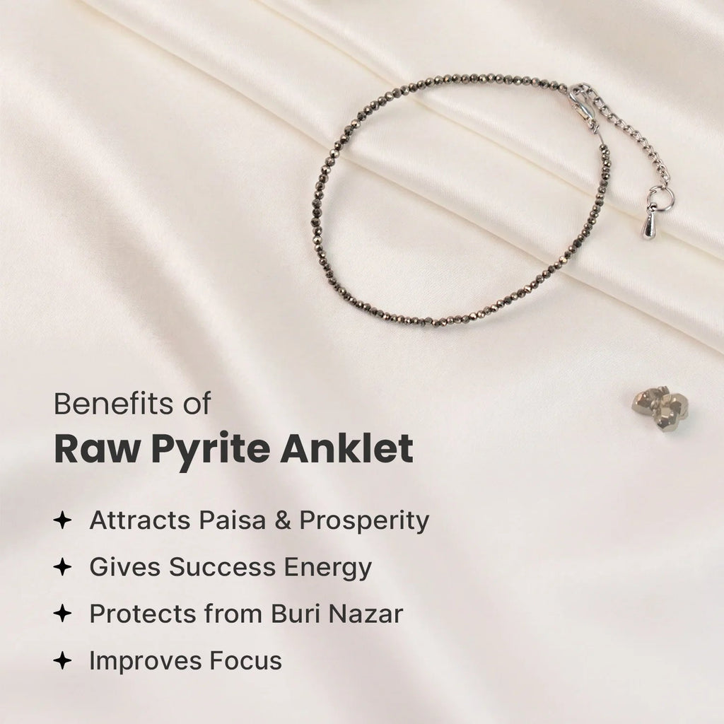 VASTUKOSHA raw pyrite anklet with metallic grey beads on a white silk background, highlighting prosperity benefits.