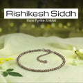 VASTUKOSHA Rishikesh Siddh raw pyrite anklet with metallic beads on a white cloth with a diya and flower petals