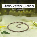 VASTUKOSHA Rishikesh Siddh raw pyrite anklet with metallic beads on a white cloth with a diya and flower petals