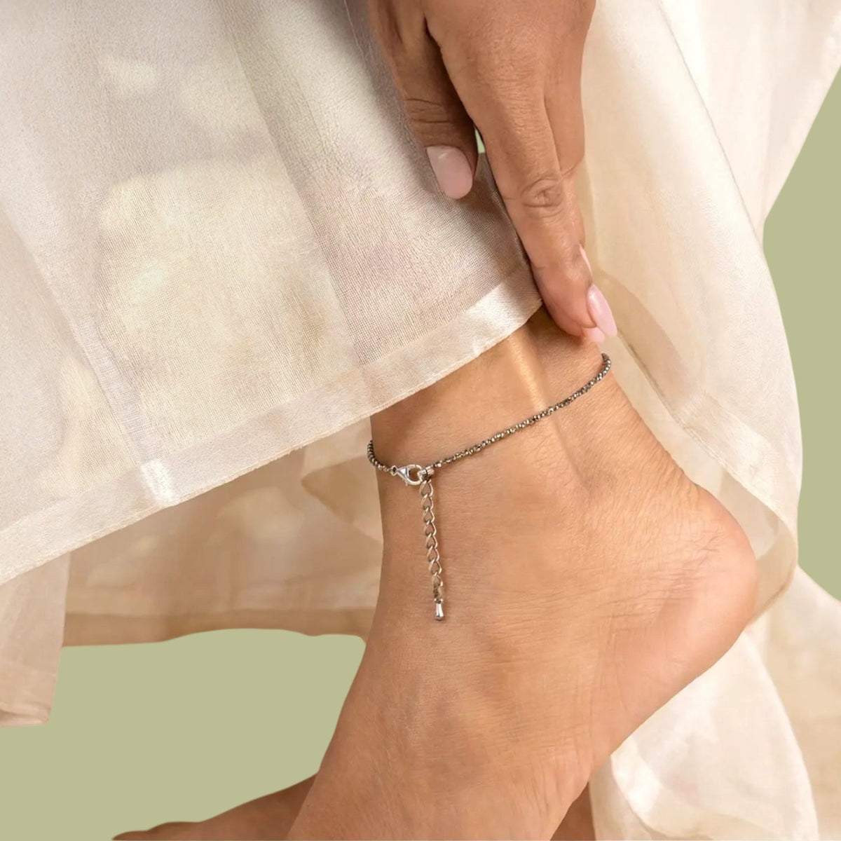 VASTUKOSHA raw pyrite crystal anklet worn on a woman's ankle, featuring metallic stone beads and a delicate chain.