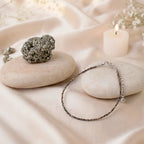 VASTUKOSHA Mahalaxmi combo featuring a raw metallic pyrite stone and a delicate beaded pyrite anklet on silk fabric.