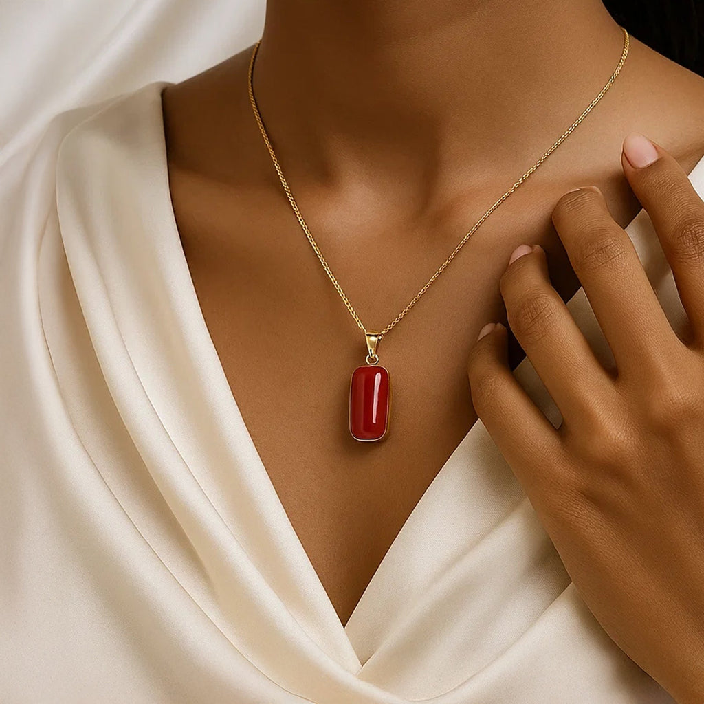 VASTUKOSHA natural red Moonga gemstone pendant on a gold chain worn by a woman in a white silk blouse