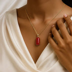 VASTUKOSHA natural red Moonga gemstone pendant on a gold chain worn by a woman in a white silk blouse